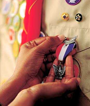 Hands clasp an eagle scout badge
