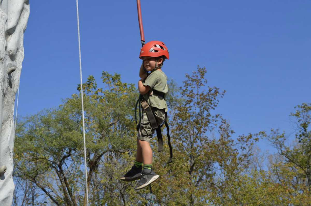 A kid holds onto safety gear used for the climbing wall