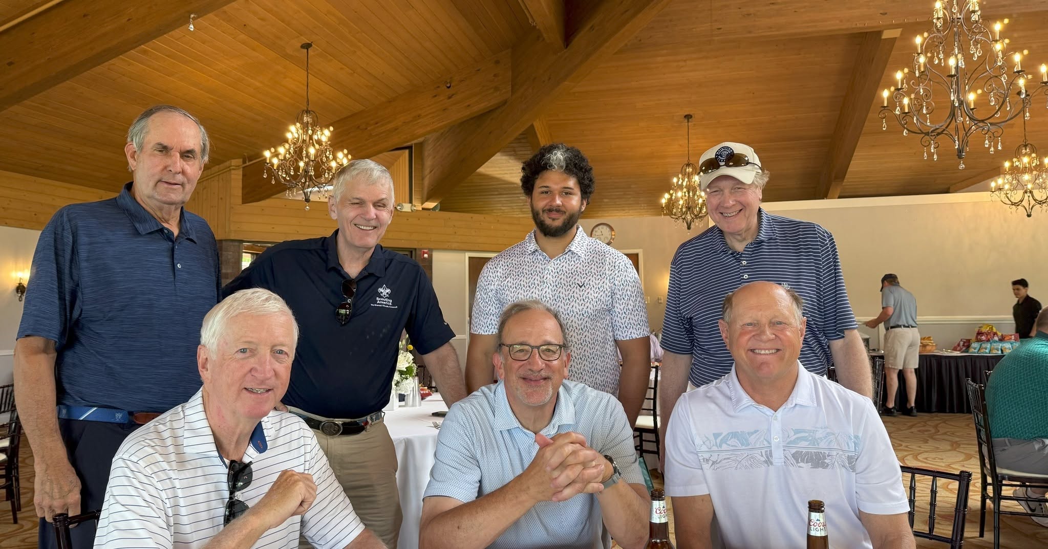 A group of people smile at the camera with fancy chandeliers behind them